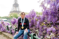 Woman in Paris, wearing a marathon medal in front of purple flowers with the Eiffel Tower in the background. College of Health Sciences Dean Keeps Busy
